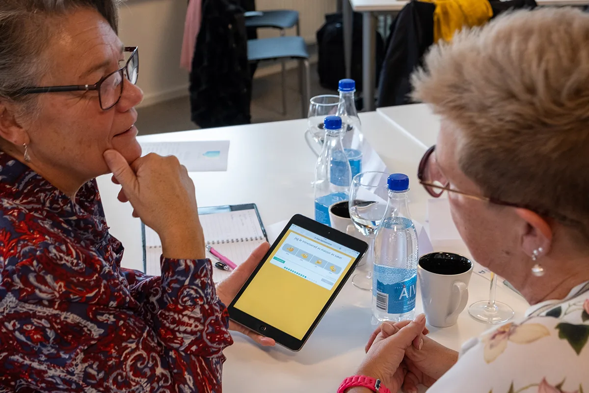 Två deltagare provar ett digitalt samtalsstöd på en surfplatta under utbildning